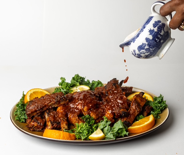 Sauce poured from a blue and white pitcher over a platter of glazed wings